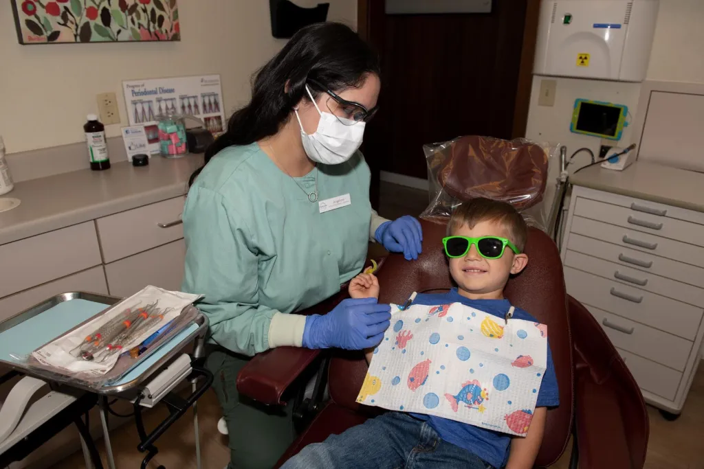 Dental Hygienist with smiling child patient in dental chair